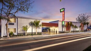 A modern hotel with a prominent sign for Studio Inn Suites, featuring a contemporary design with a flat roof and large windows. - Studio Inn and Suites at Promenade Downey (Downey)