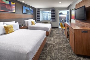 Une chambre d’hôtel avec deux lits, un bureau, une télévision et une vue sur l’extérieur.