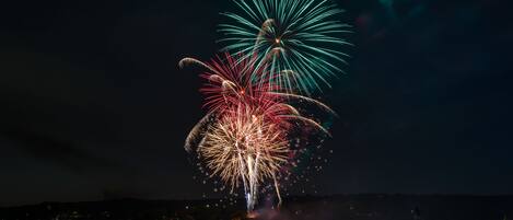 A nighttime view of a waterfront with fireworks display.