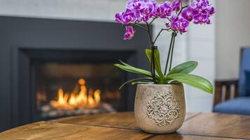 A potted orchid on a wooden table with a fireplace in the background.