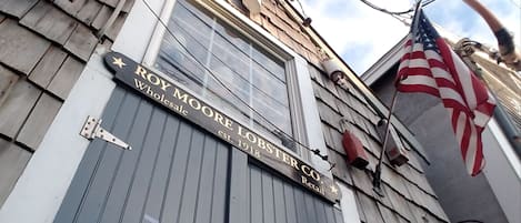 Une devanture de magasin avec une enseigne indiquant « ROY MOORE LOBSTER CO. Vente au détail » et un drapeau américain.