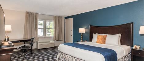 Una habitación de hotel con una cama grande, un escritorio, una silla y una ventana con cortinas.