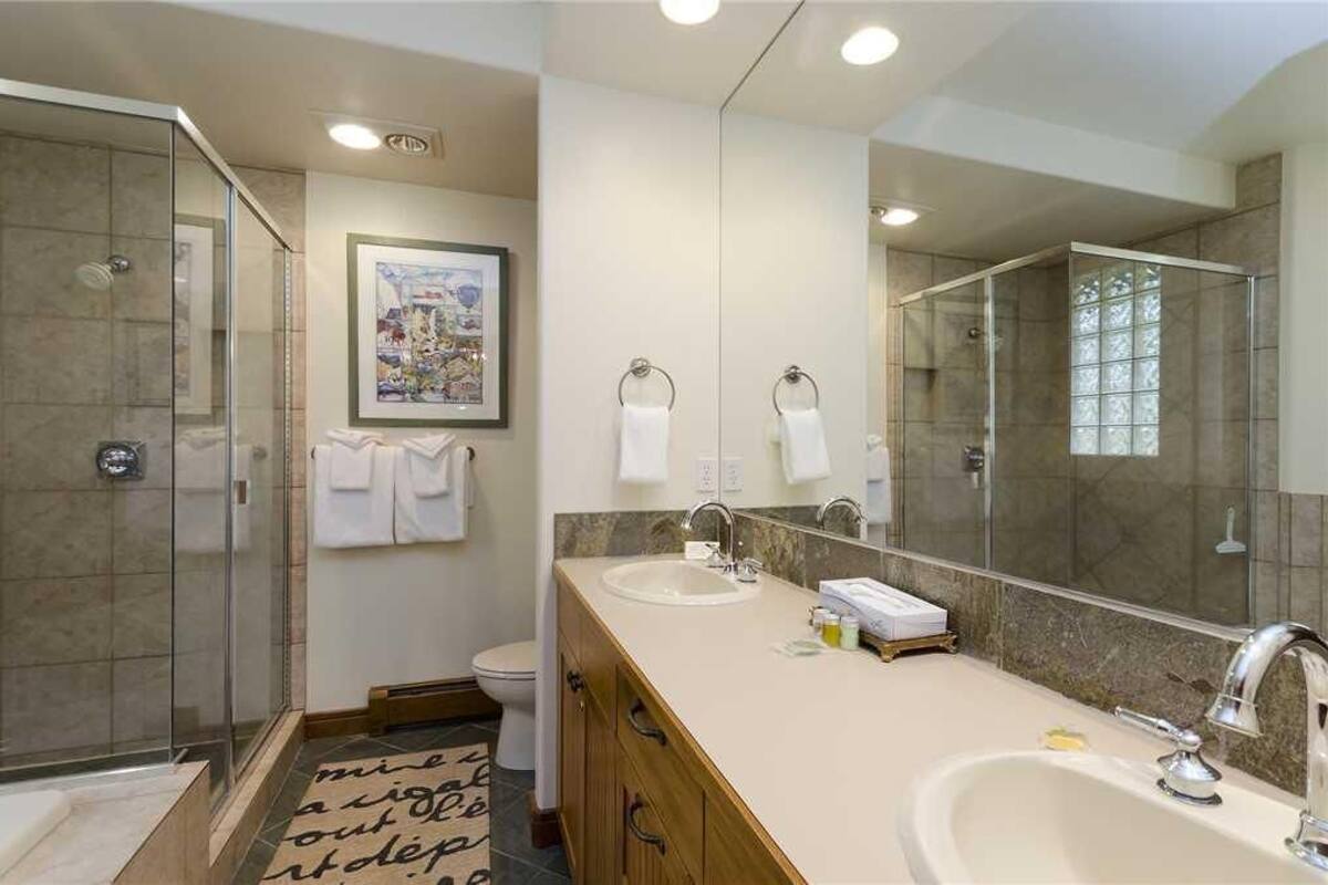 A modern bathroom with a glass shower enclosure, a large mirror, and a vanity with a sink and countertop.