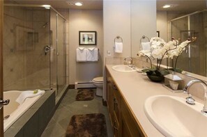 A modern bathroom with a glass-enclosed shower, a bathtub, two sinks, and a large mirror. - The Trails at Storm Meadows by Mountain Resorts (Steamboat Springs)