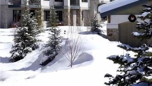 Un hôtel à plusieurs étages, doté de balcons, entouré de montagnes et d’arbres couverts de neige.