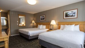 Une chambre d’hôtel avec deux lits, un bureau et un miroir.