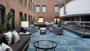 A modern hotel lobby with a brick facade, a seating area with sofas and chairs, and a patterned carpet. - Courtyard by Marriott Philadelphia Downtown (Philadelphia)