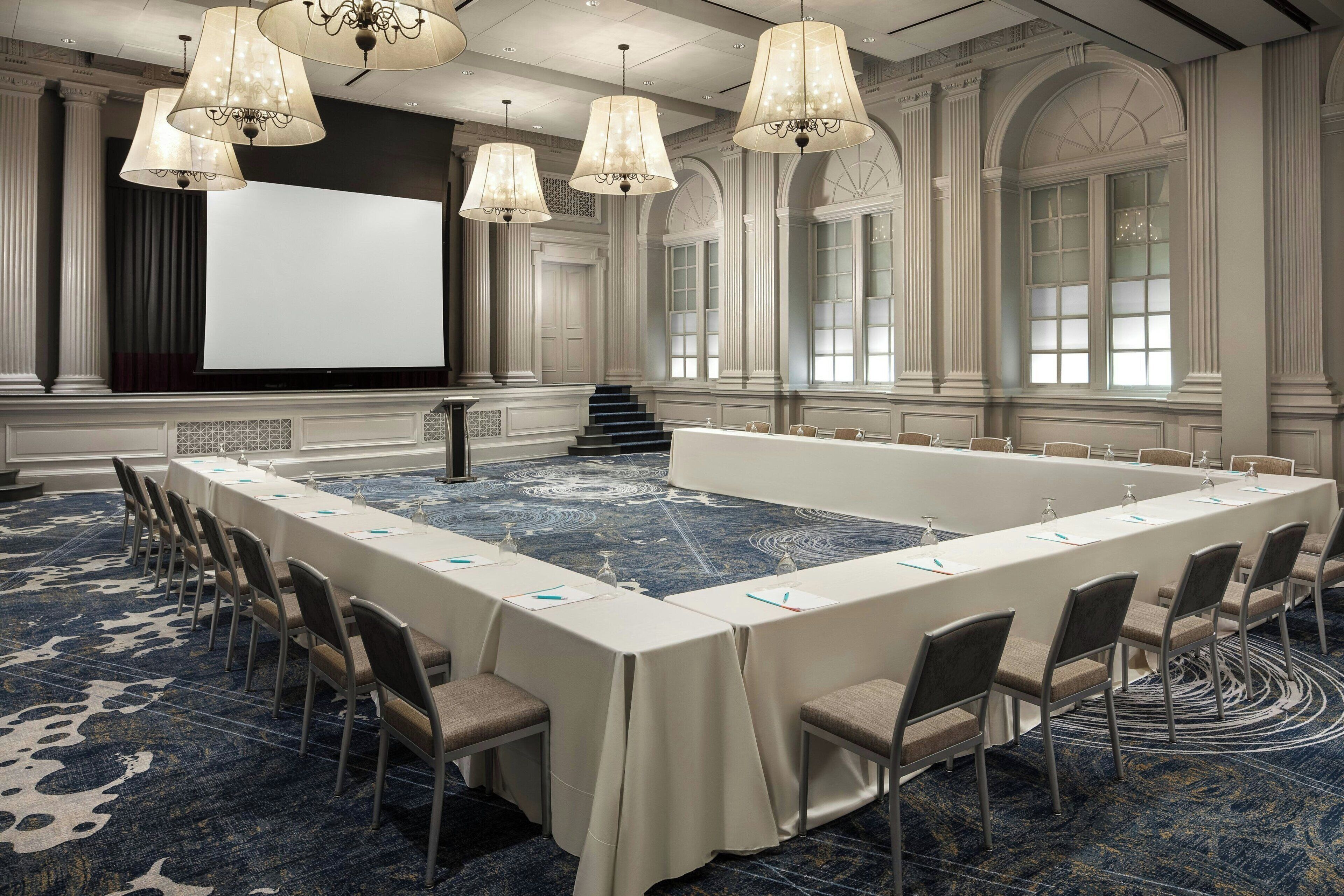 A conference room with a long table, chairs, and a projector screen.