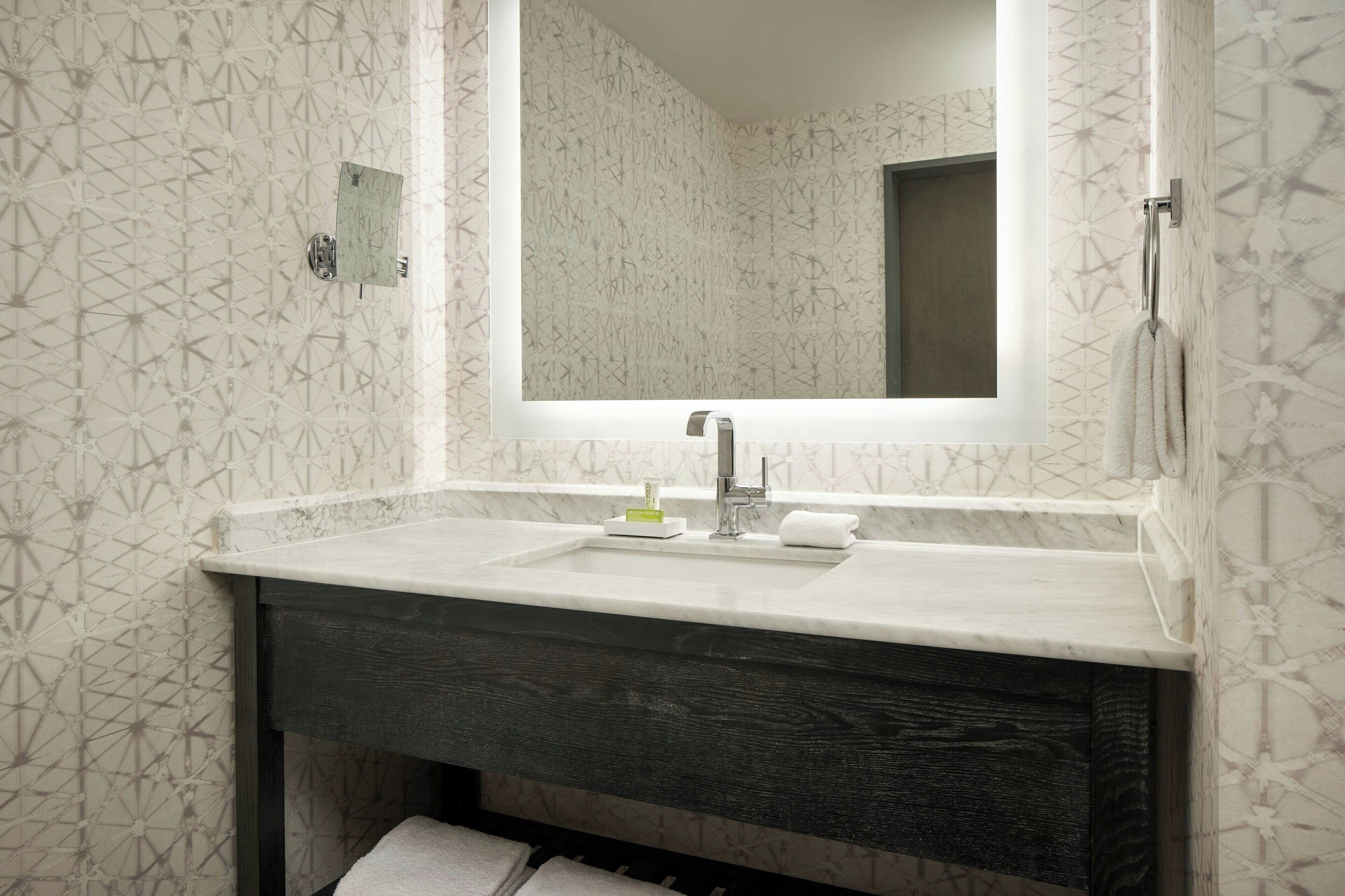 Un baño con un espejo grande, dos lavamanos y un mueble de tocador de madera oscura.