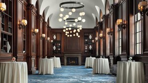 A grand hall with a blue patterned carpet, multiple round tables with white tablecloths, and a large circular chandelier. - Courtyard by Marriott Philadelphia Downtown (Philadelphia)