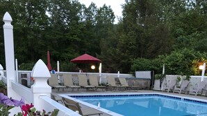A swimming pool with lounge chairs and a white fence. - Lyn Aire Motel (Lake George)
