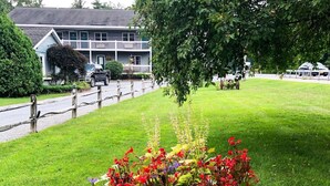 A garden with a variety of colorful flowers in a large, weathered planter. - Lyn Aire Motel (Lake George)