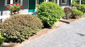 A single-story motel with a covered porch, green doors, and a gravel driveway. - Lyn Aire Motel (Lake George)