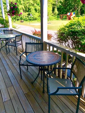 Une terrasse en bois avec une table ronde et des chaises, le tout entouré d’une rambarde.