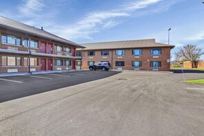 Un motel con estacionamiento, un edificio de dos pisos y otro de un solo piso al fondo.