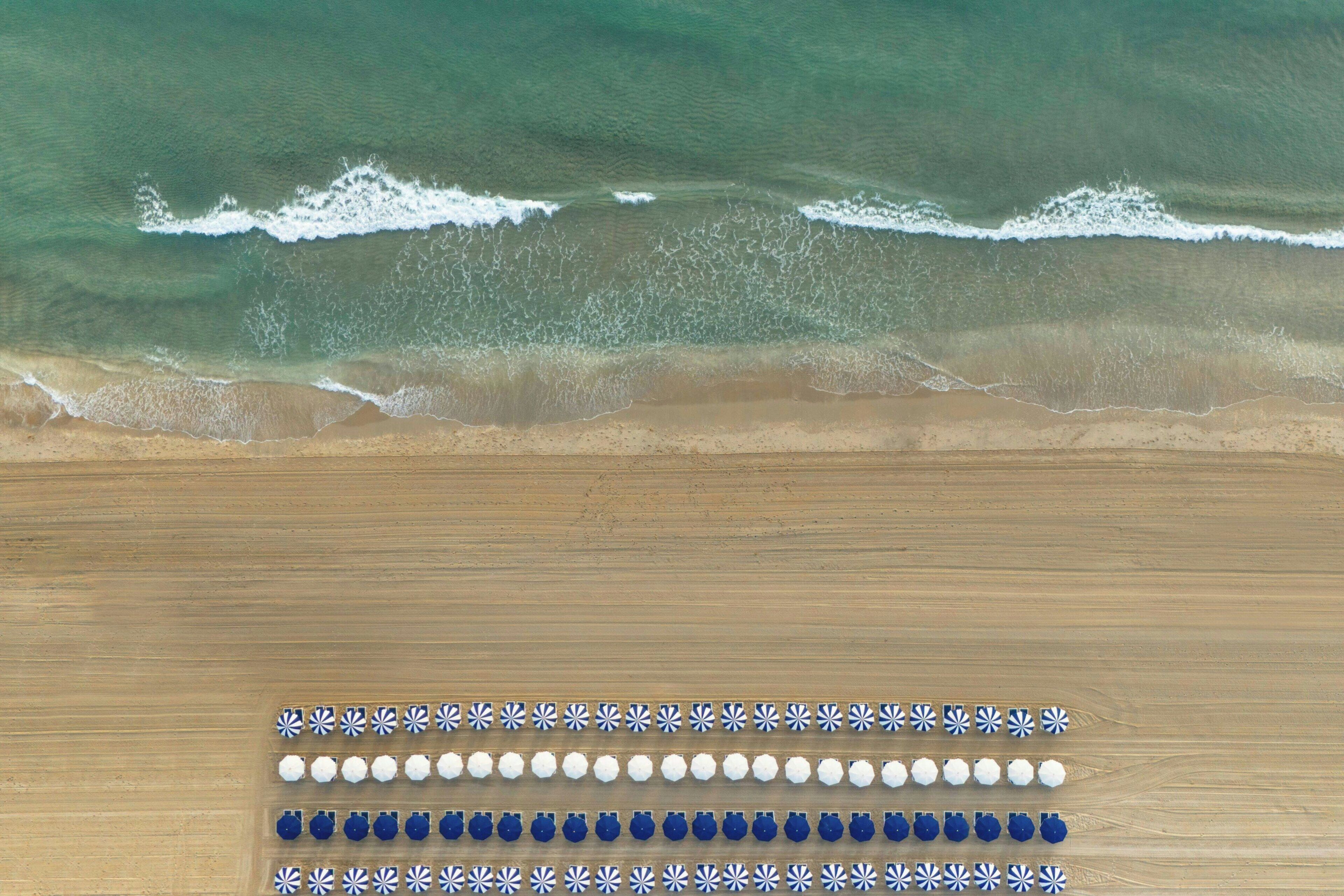 A beach with waves and a wooden surface with rows of blue and white objects.