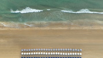 A beach with waves and a wooden surface with rows of blue and white objects.