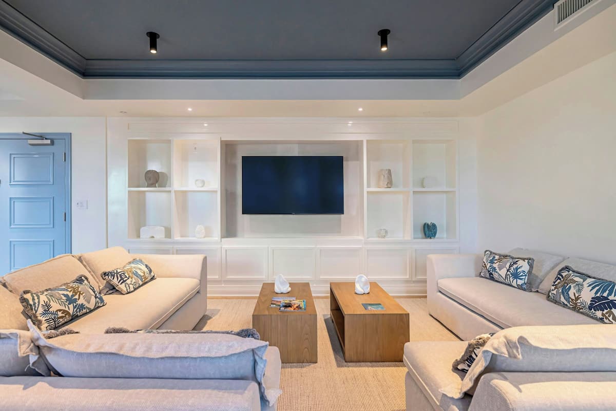 Ein modernes Wohnzimmer mit zwei Sofas, einem Couchtisch und einem Flachbildfernseher, der an einer weißen Wand angebracht ist.
