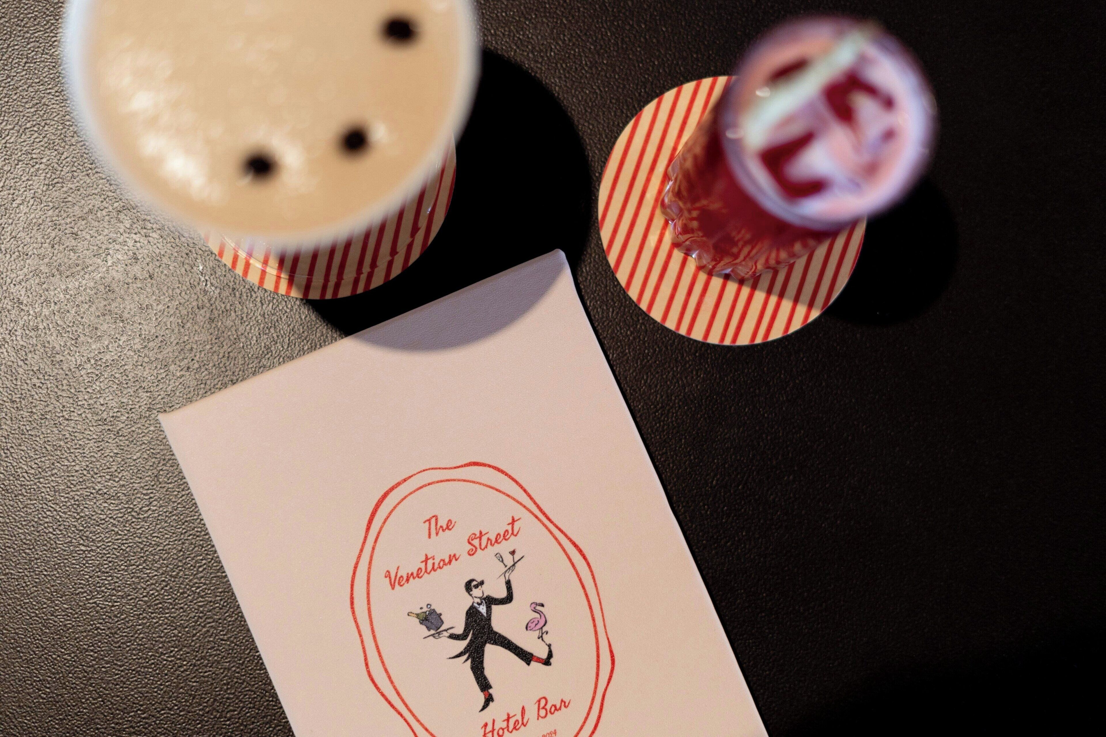 A menu from The Venetian Street Hotel Bar, featuring a drink with a straw and a dessert with a cherry on top.