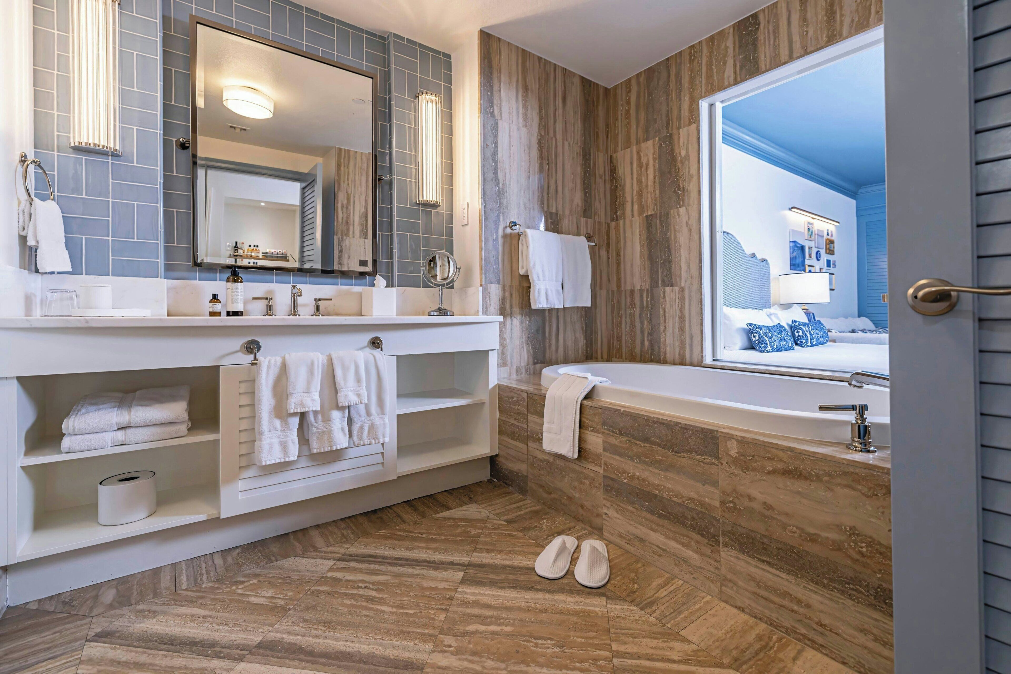 A modern bathroom with a large mirror, white vanity, and a bathtub.