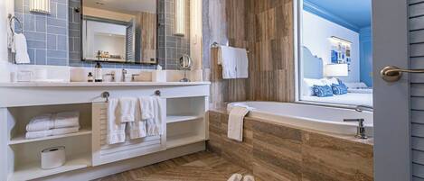 A modern bathroom with a large mirror, white vanity, and a bathtub.