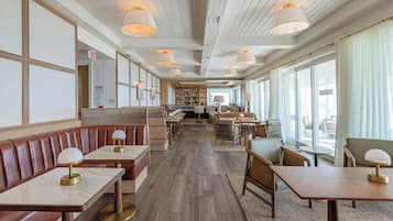 A spacious restaurant with wooden floors, leather booths, and tables with lamps.