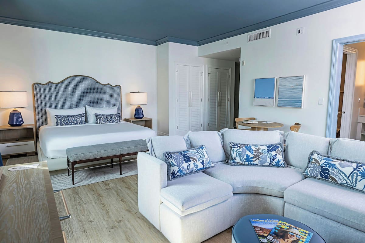 Ein modernes Hotelzimmer mit einem Bett, einem Sofa, einer Bank und einem kleinen Tisch.
