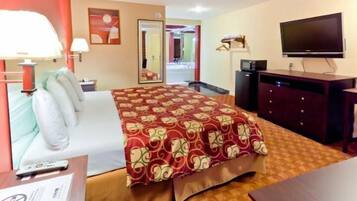 Habitación de hotel con cama, escritorio, teléfono, televisión y espejo.