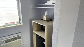 A compact bathroom with a window, a towel rack, a shelf with toiletries, and a built-in heater. - Monaco Motel - Wildwood Beach & Boardwalk (Wildwood)