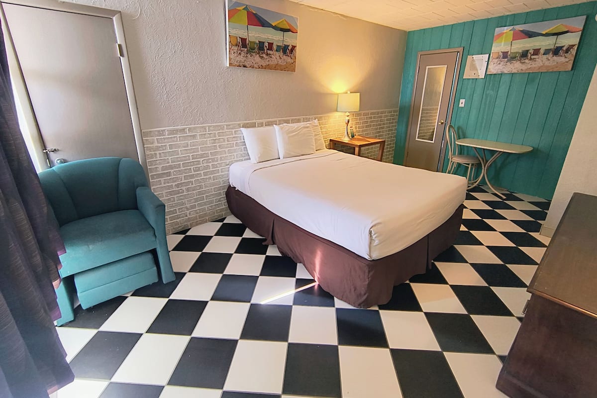 Ein Zimmer mit Bett, Stuhl, Tisch und Tür.