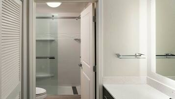 A bathroom with a toilet, a shower, and a sink.