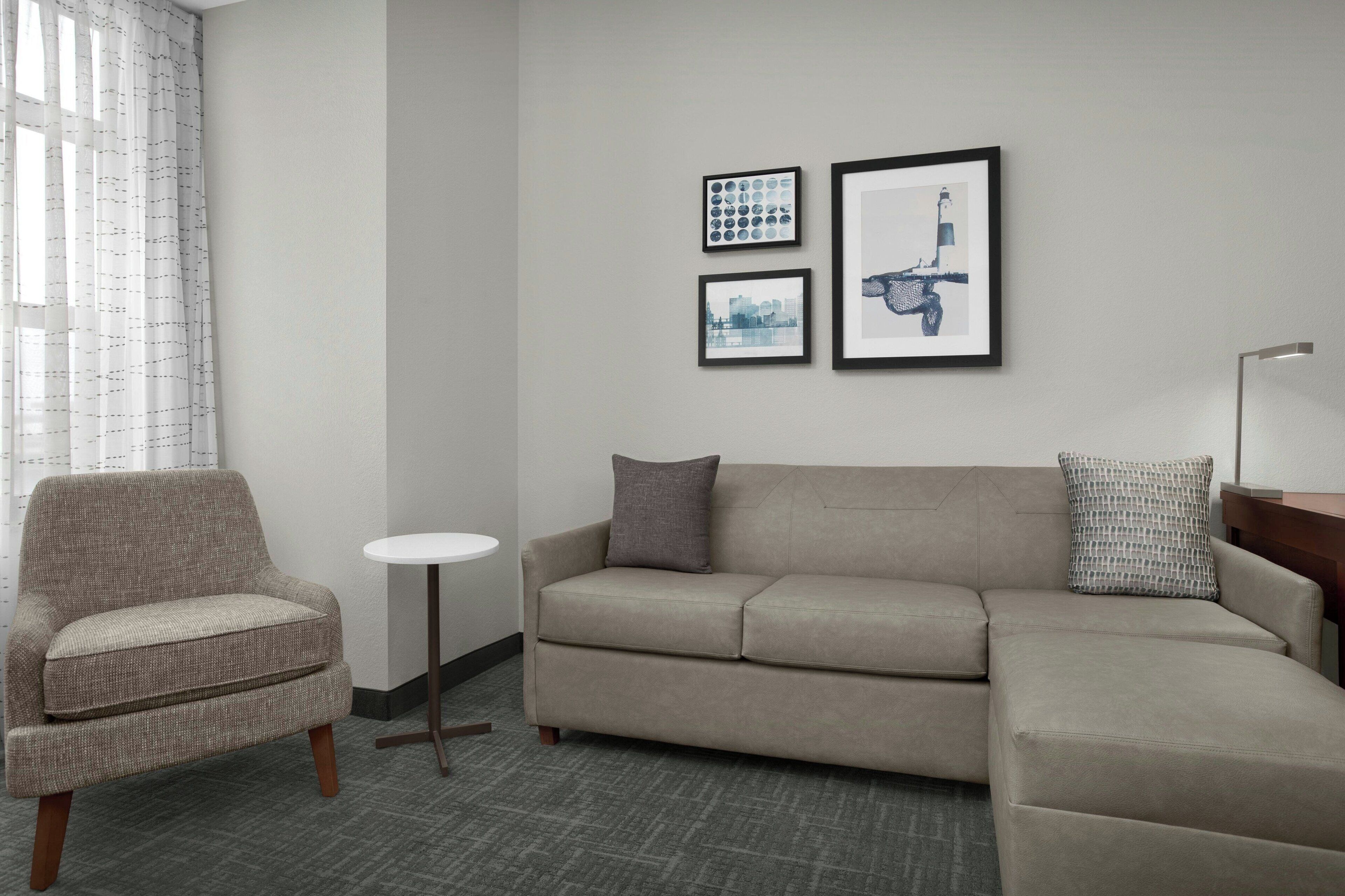 A modern living room with a sofa, armchair, and a small round table.