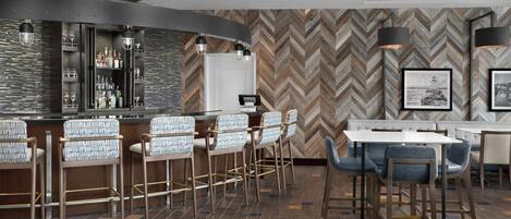 A bar area with stools, a counter, and a herringbone-patterned wall.