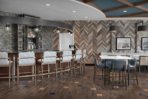 Eine Bar mit Barhocker, einer Theke und einer Wand mit Fischgrätmuster.