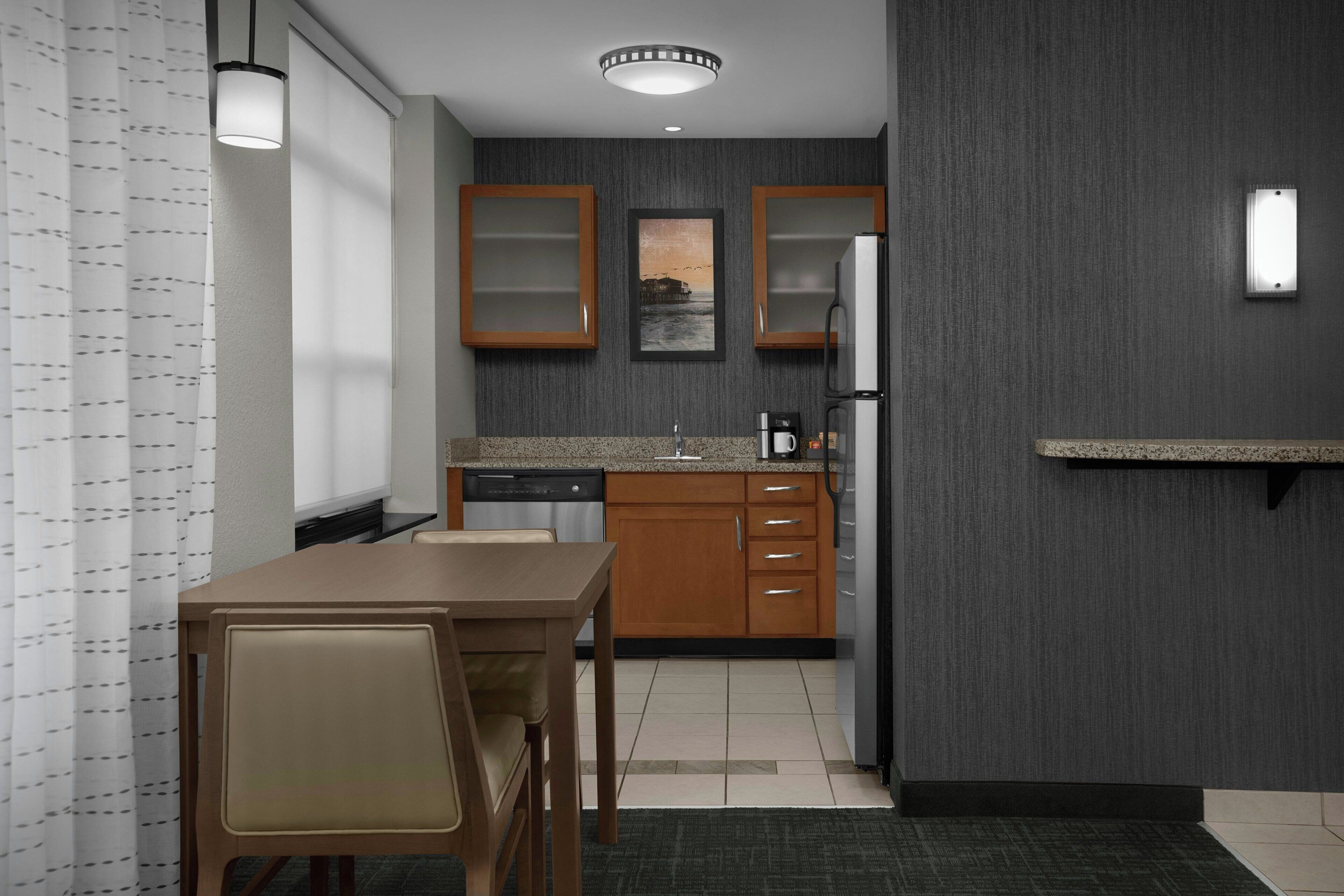 A compact kitchen with wooden cabinets, a countertop, and a dining area with a table and chairs.