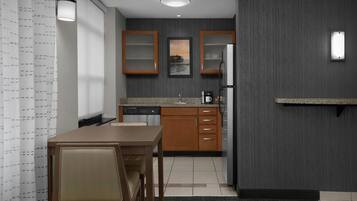 A compact kitchen with wooden cabinets, a countertop, and a dining area with a table and chairs.