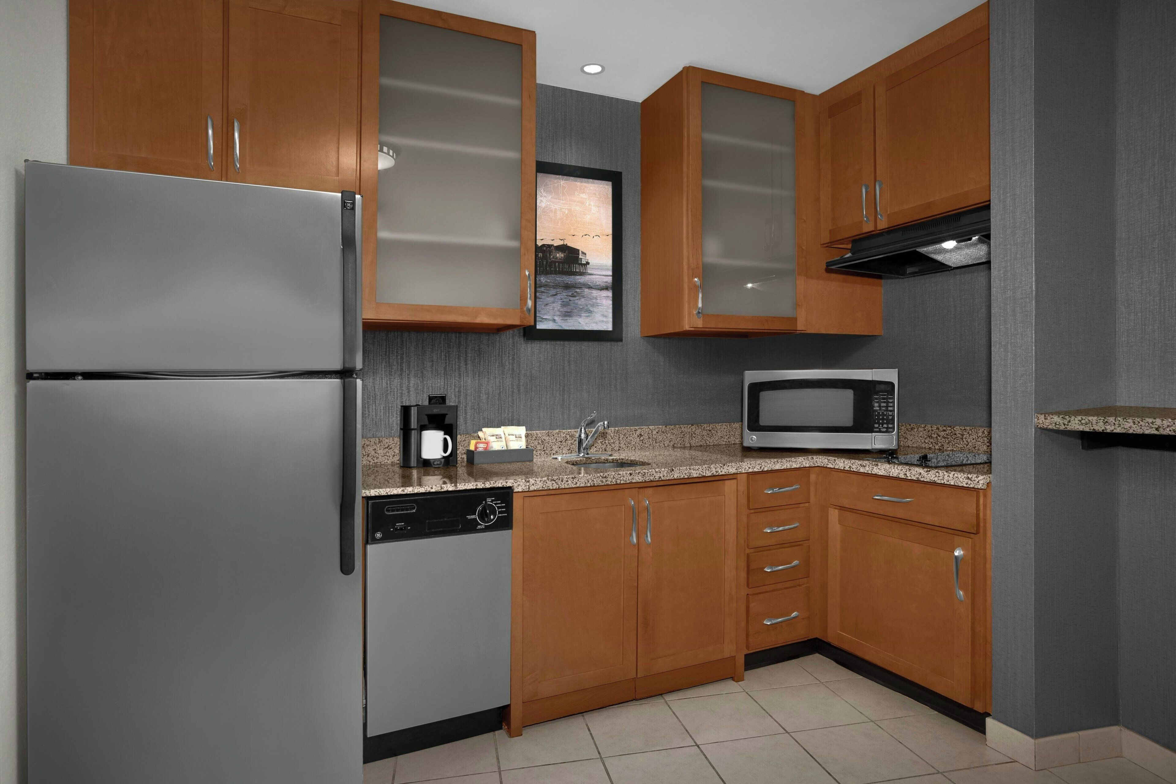 Una cocina con armarios de madera, un refrigerador de acero inoxidable, un microondas y un lavavajillas.