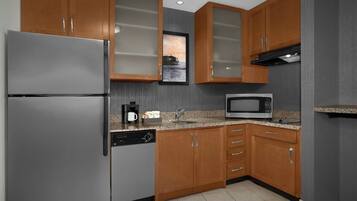 A kitchen with wooden cabinets, a stainless steel refrigerator, a microwave, and a dishwasher.