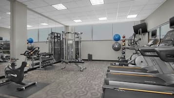 Academia com esteiras, aparelhos de musculação e bolas de exercício.