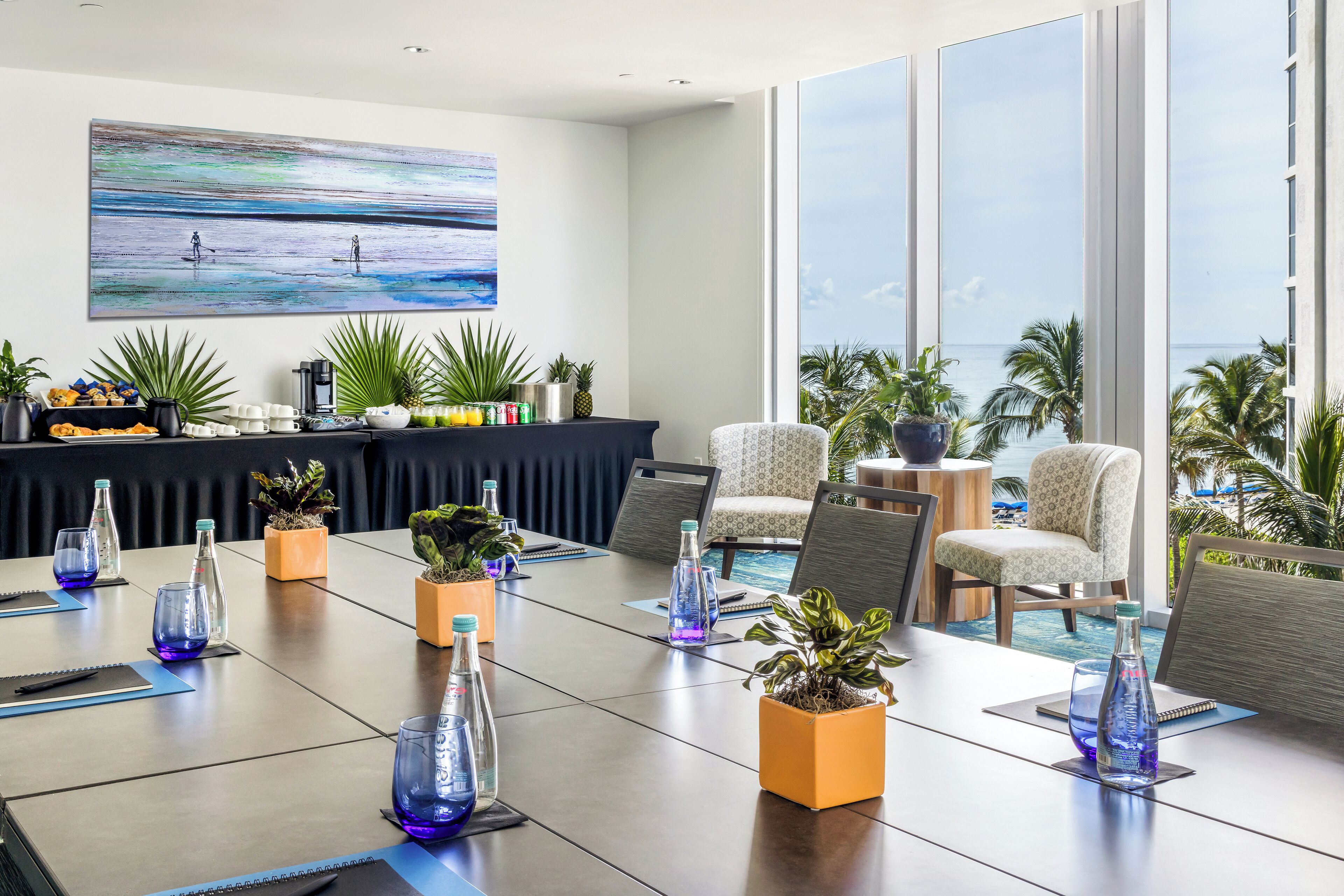 A conference room with a large table, chairs, and potted plants.