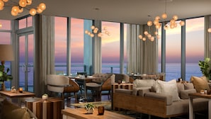 Een moderne hotelkamer met een prachtig uitzicht op de oceaan, meerdere zithoeken en een eigentijdse inrichting.