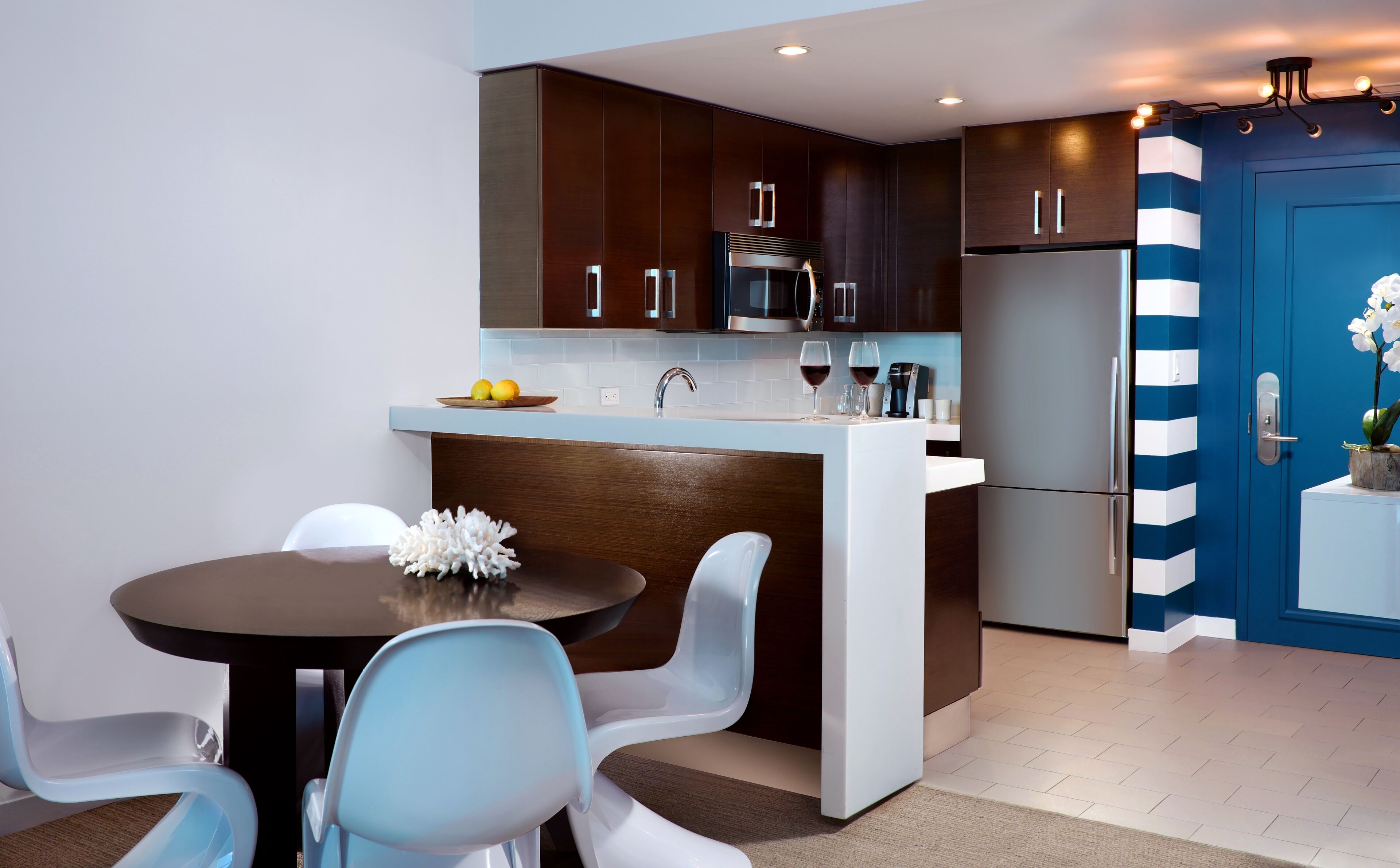Eine moderne Küche mit dunklen Holzschränken, einem Edelstahlkühlschrank und einer blauen Tür.