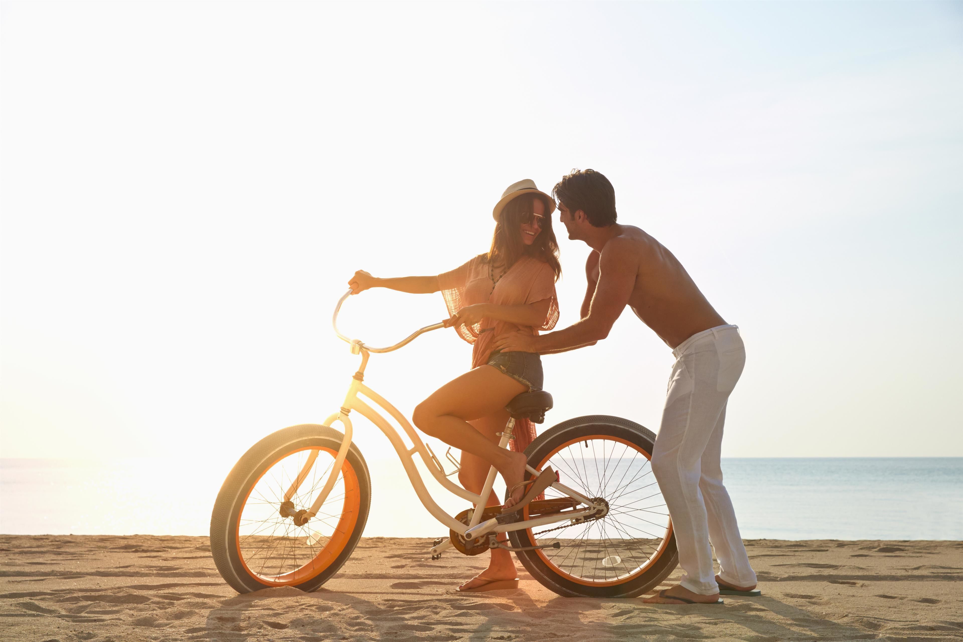 A couple on a beach with a bicycle.