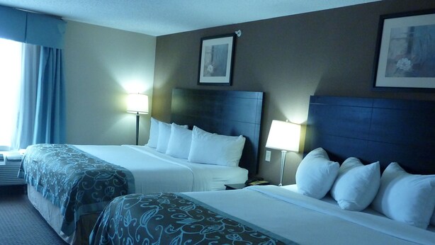 Une chambre d’hôtel avec deux lits, chacun doté d’une tête de lit, de lampes de chevet et d’une fenêtre avec des rideaux.