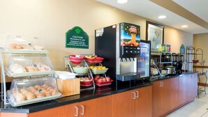 Un comptoir de petit-déjeuner avec divers aliments, un panneau d’avertissement, une machine à café et un réfrigérateur.