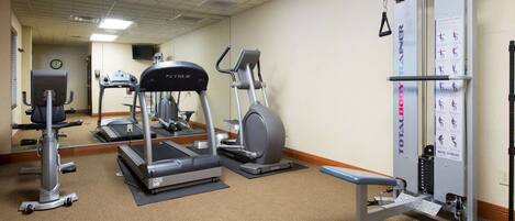 A hotel fitness center with treadmills, elliptical machines, and a total body trainer.