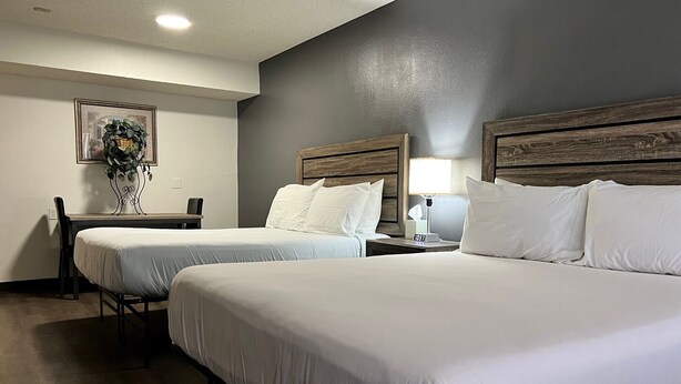 Quarto de hotel com duas camas, uma escrivaninha e uma cadeira.
