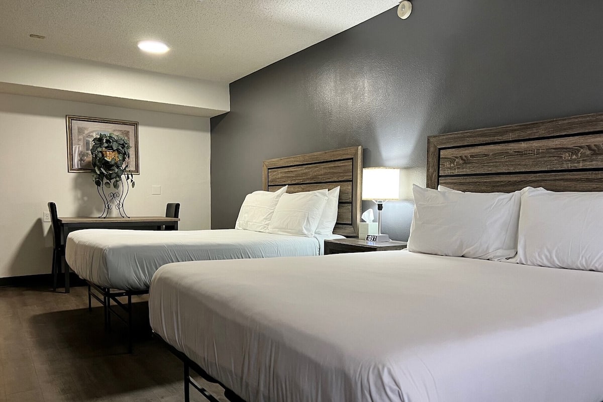 A hotel room with two beds, a desk, and a chair.