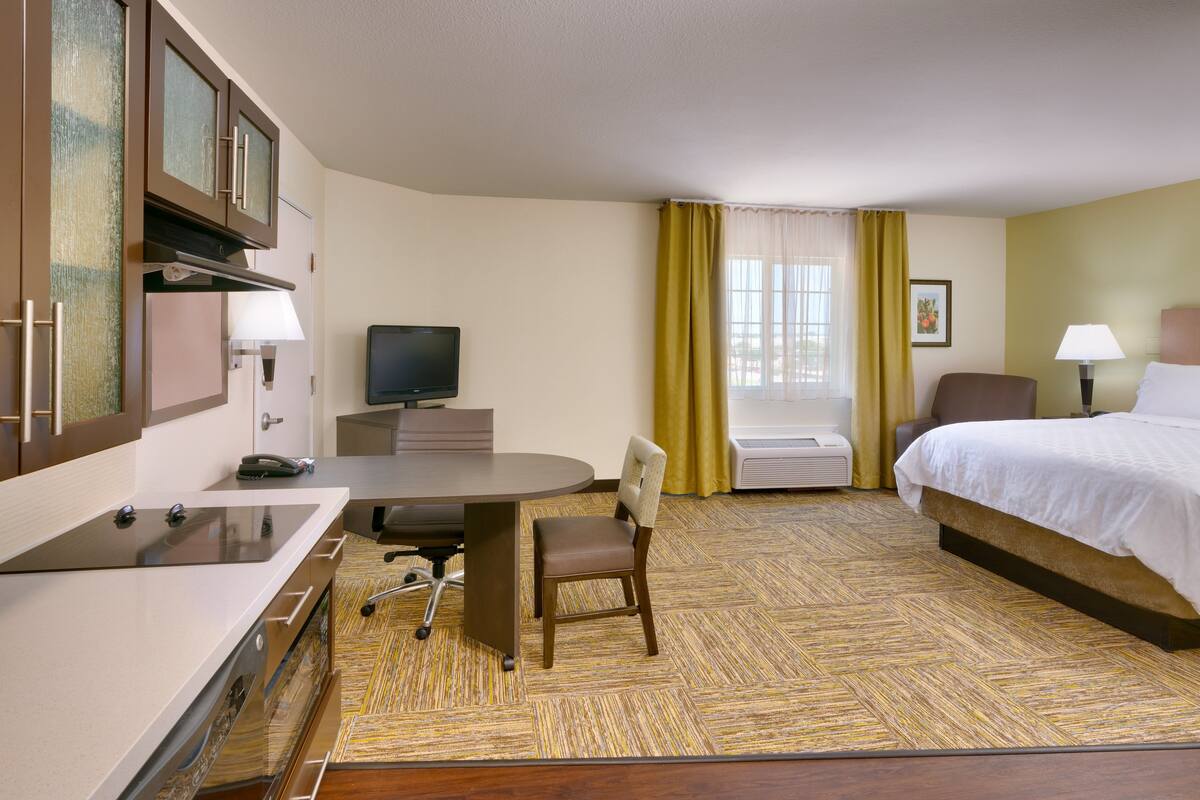 Une chambre d’hôtel équipée d’un lit, d’un bureau, d’une chaise, d’une télévision et d’une fenêtre avec des rideaux.