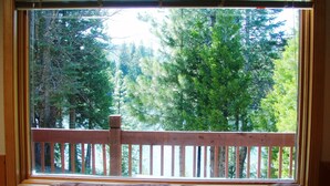Una ventana con vista a una terraza de madera y árboles.